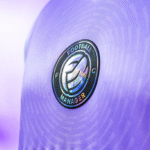 Close up of a player's chest in a lavender purple shirt, showing a Football Manager FC club badge in the middle