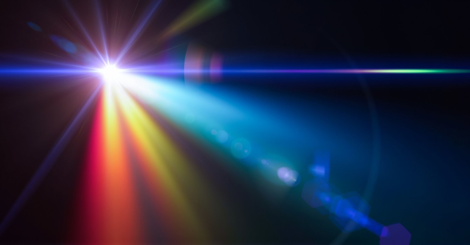 a single bright, white source of light against a black background, with lens flare and a prism effect creating a complex mix of different colored light rays.