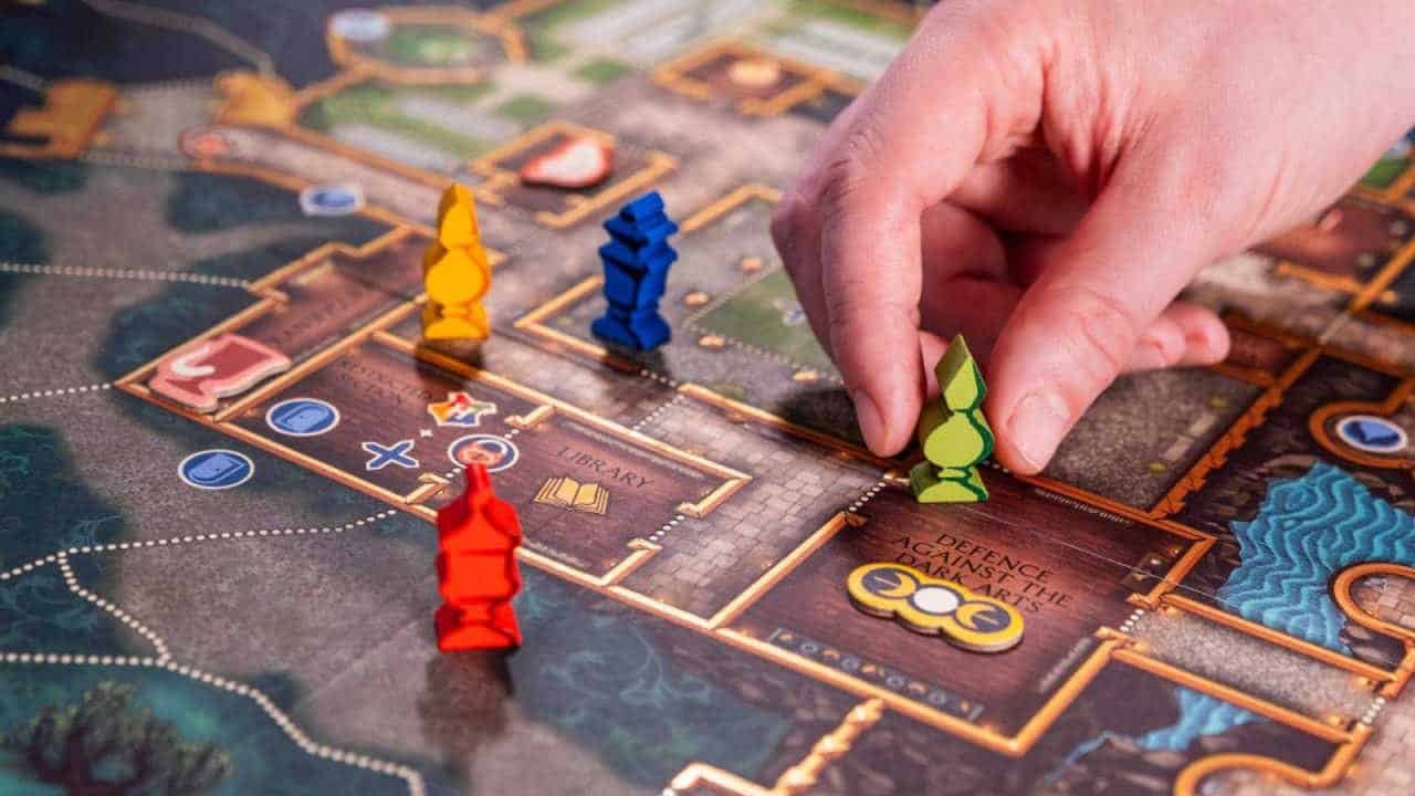 A hand moving pieces across a board in Harry Potter Defenders of Hogwarts.