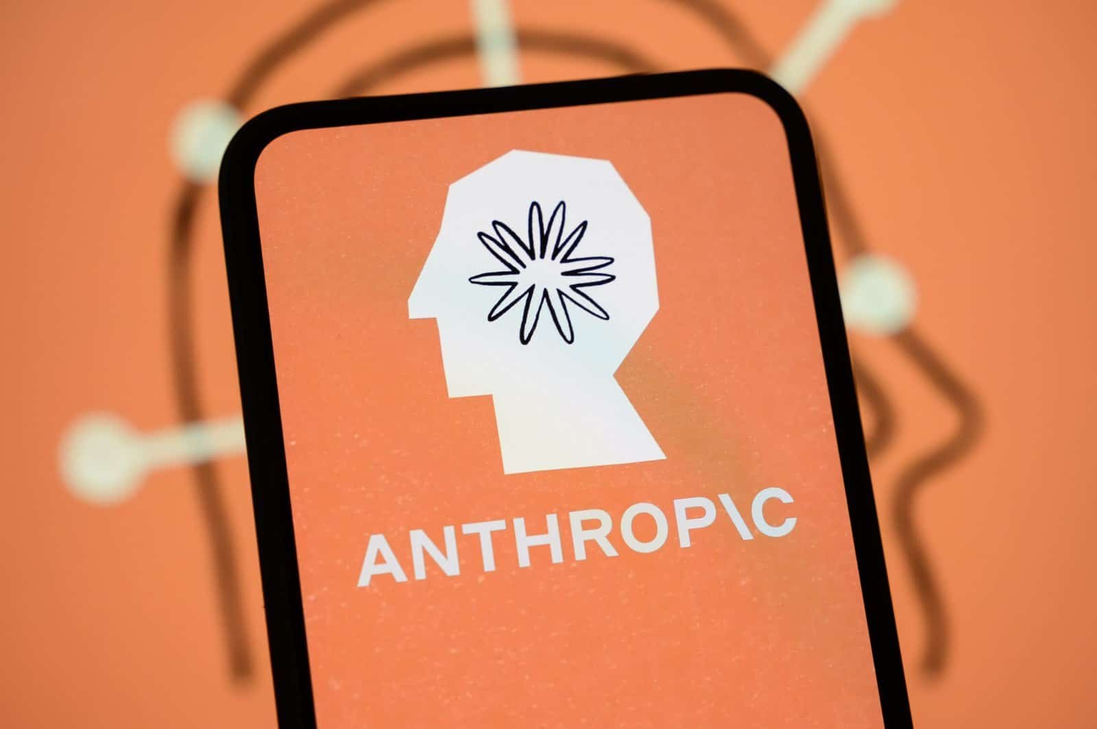 The Anthropic logo is displayed on the screen of a smartphone with the company's branding in the background.