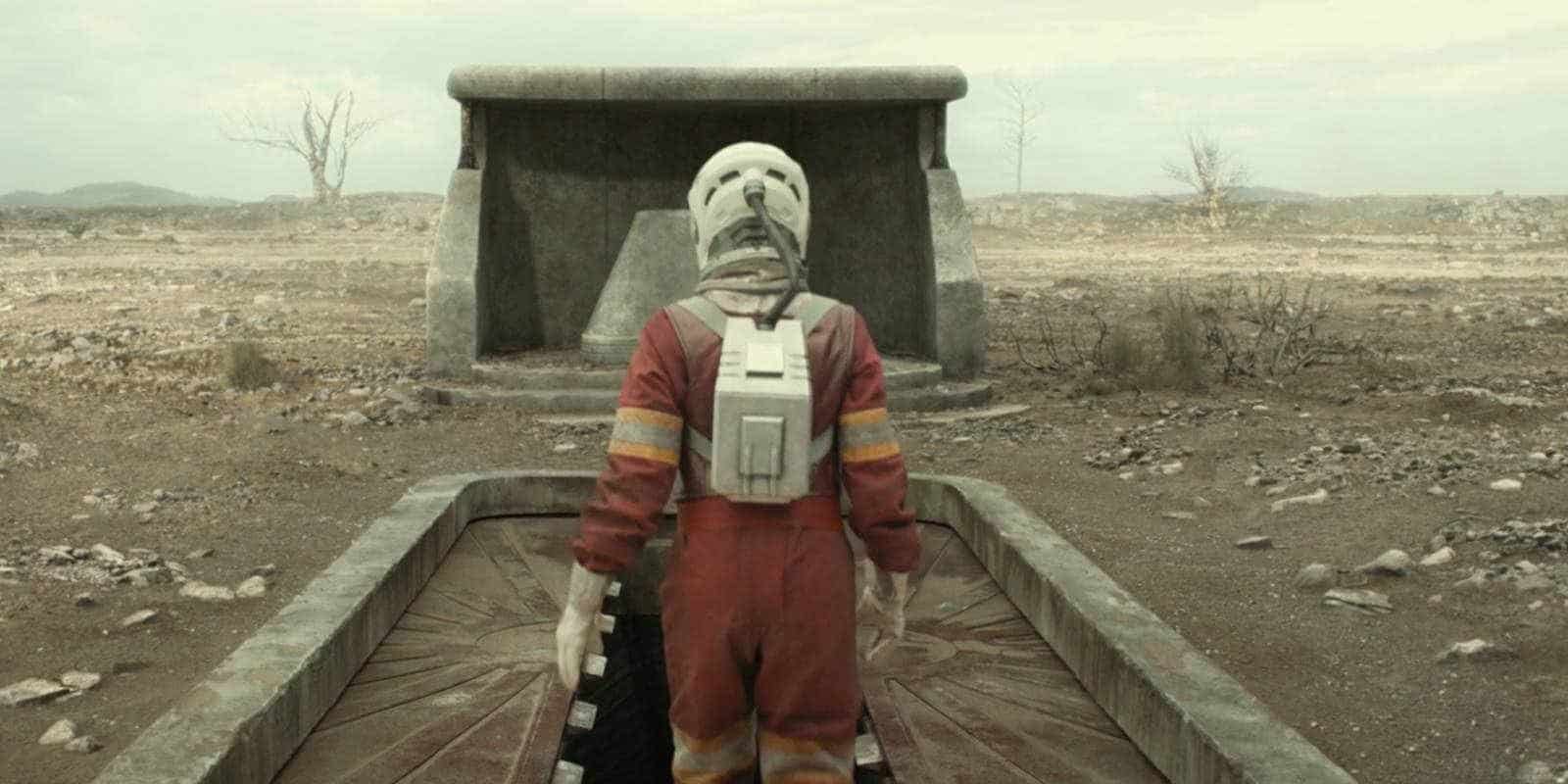Juliette (Rebecca Ferguson) entering Silo 18 in season 2, wearing an orange space-like suit with her back turned to the camera
