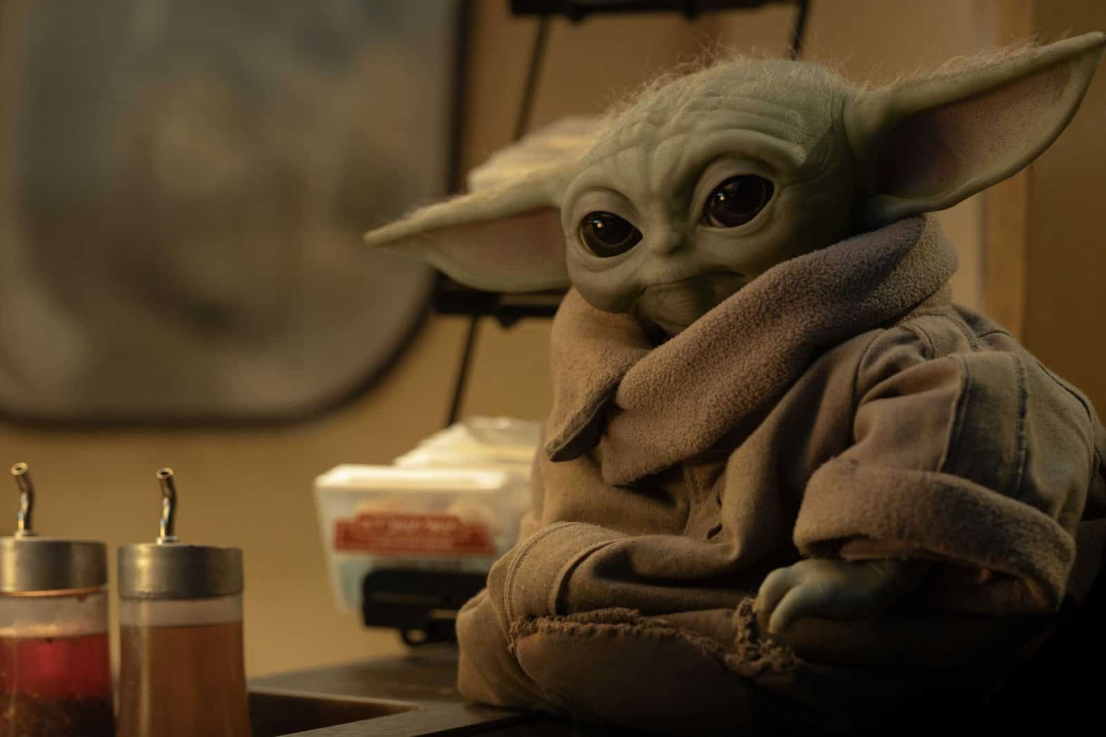 Grogu sits by some sauce dispensers in The Mandalorian and Grogu