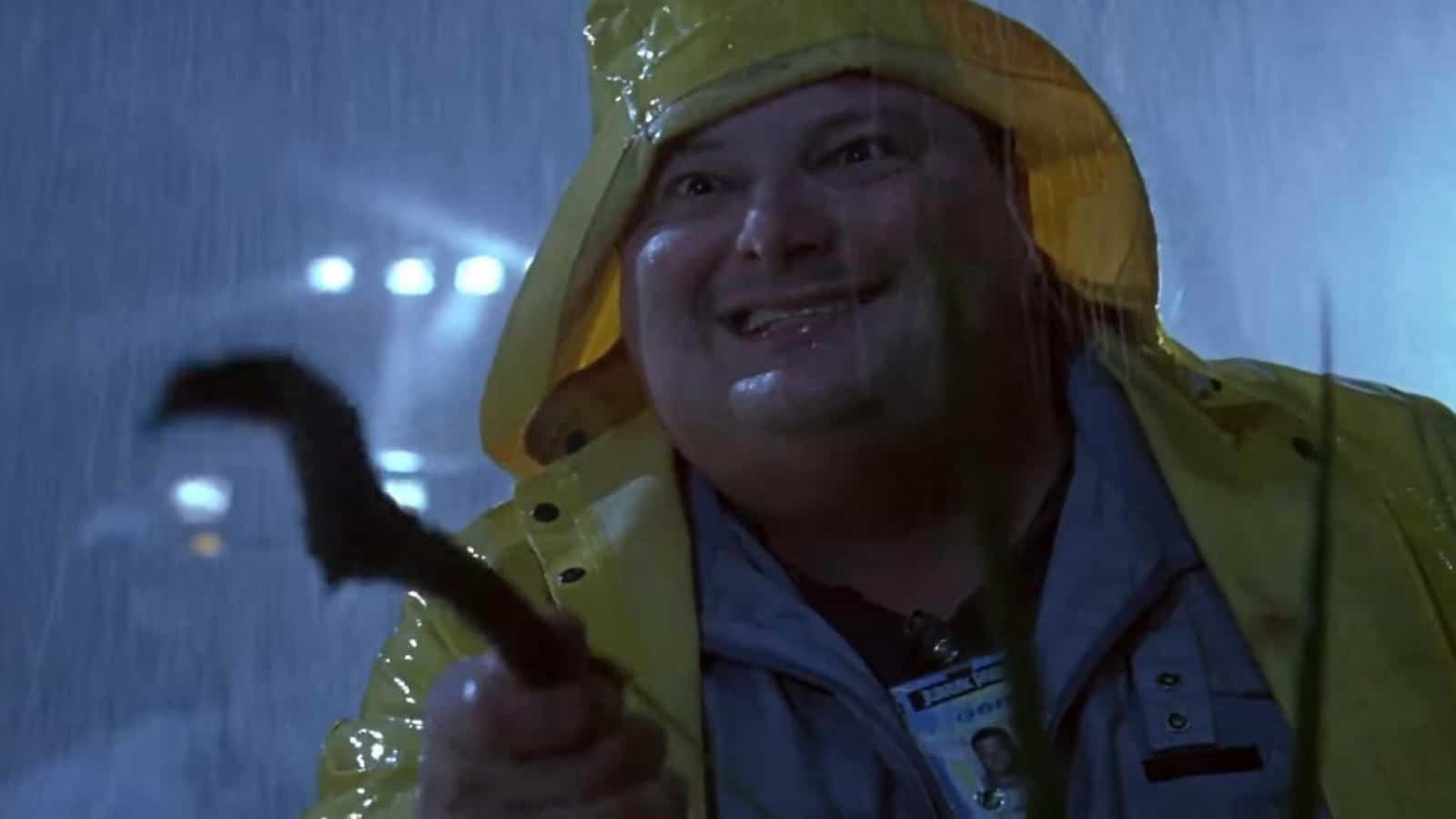Dennis Nedry holding a stick trying to play with a dilophosaurus in Jurassic Park