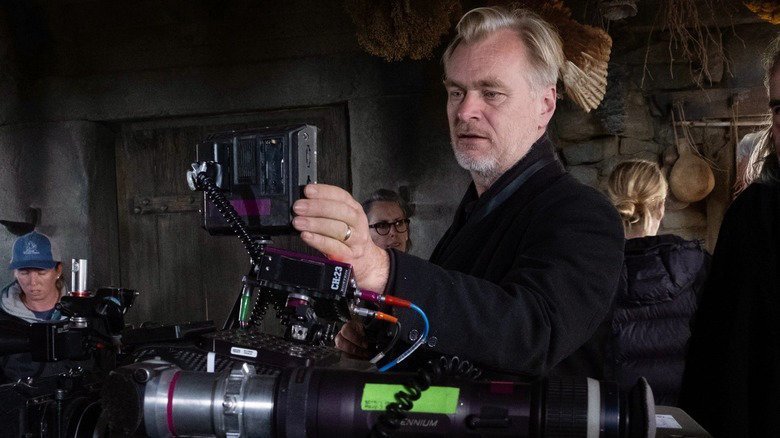 Christopher Nolan looks into the screen of an IMAX camera during the filming of The Odyssey