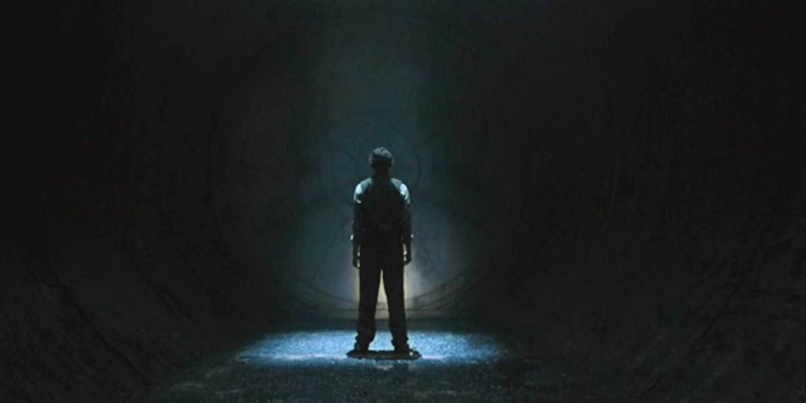 Avi Nash as Lukas Kyle standing in front of a mysterious vault door in Silo
