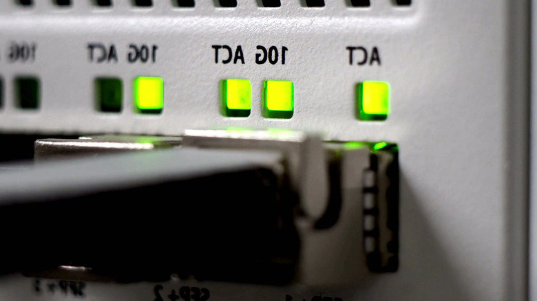 Close-up of Ethernet cables plugged into network ports beside green status lights.
